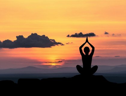 A person meditating on a mountain.