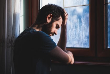 A sad man at a window.