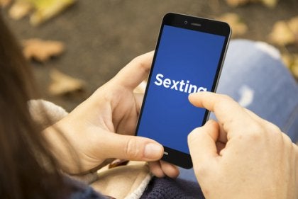 The word sexting on a smartphone screen.