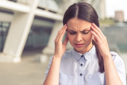 A woman with a furrowed brow pressing on her temples.