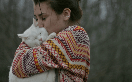 A woman hugging and kissing a cat.