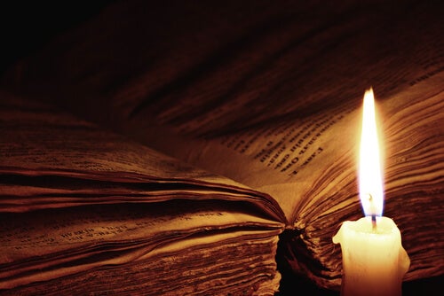 An open book by a candle light.