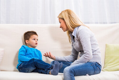 A mom sitting on the couch with her son, explaining something to him.