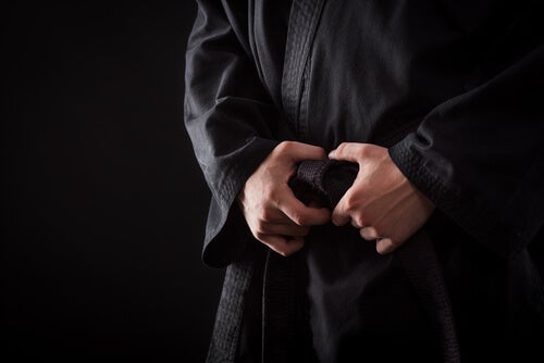A person with their hands clasped around their martial arts belt.