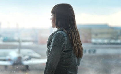 A woman looking out the window at an airport.