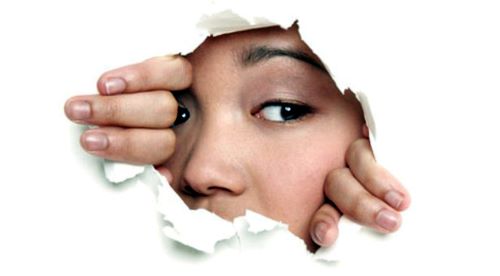 Vrouw kijkt door gat in de muur