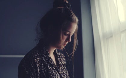A woman standing by a window.