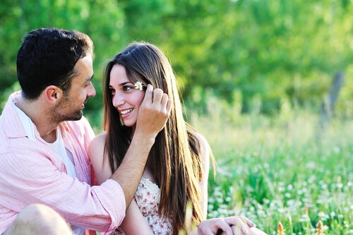A couple sitting together in a field, looking into each other's eyes. 