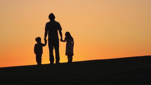 A father holding his children's hands.