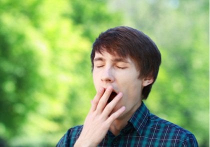 A guy yawning outside.