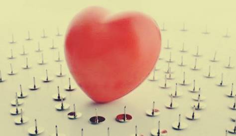 A heart balloon standing on the ground, surrounded by pins. 