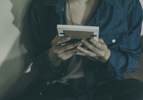 A person looking at a framed photo in their hands.