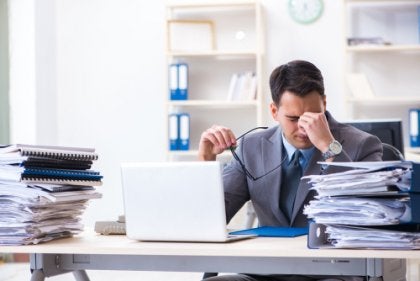 A stressed guy at work with piles of papers.