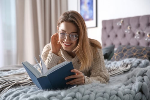 A woman living apart from her partner lying in bed reading a book.