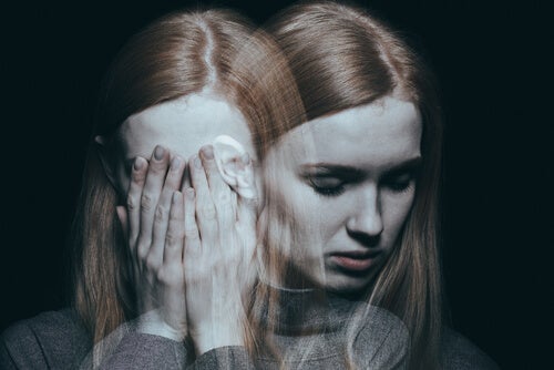A woman with her hands on her face, and a mirror image of herself hovering next to her shoulder.