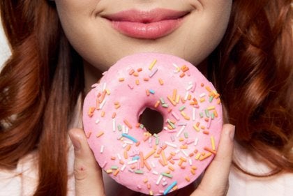 A woman with an iced pink donut.