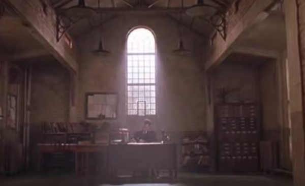 A man sitting at a desk in a musty room in a prison.