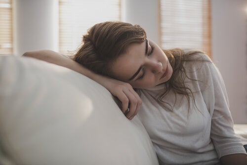 A woman with depression laying her head on her couch.