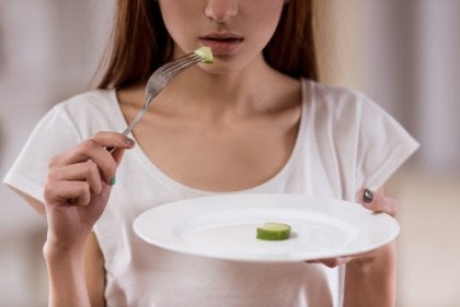 A girl with anorexia eating a cucumber slice.