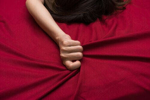 A woman clutching bedsheets. 