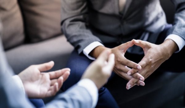 A close-up showing two people's hands as they have a conversation.