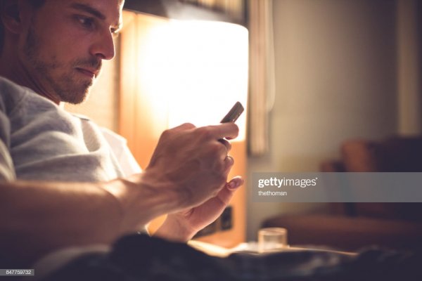 A man with his cellphone in bed.