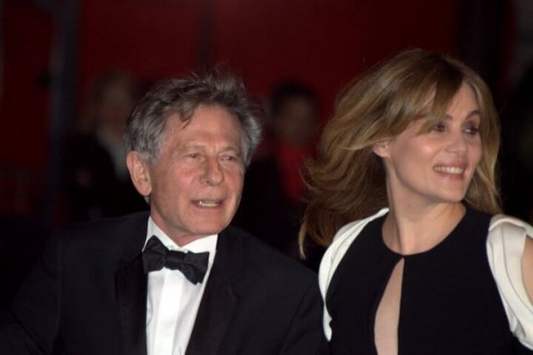 Roman Polanski standing on the red carpet with his wife.