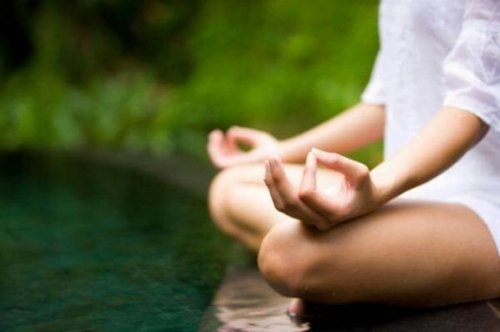 A woman meditating by the water.