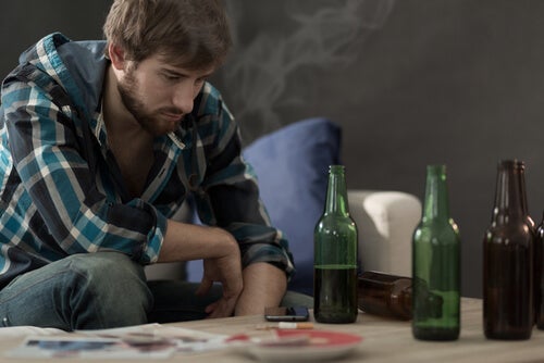 A man staring at bottle sof alcohol on a table.