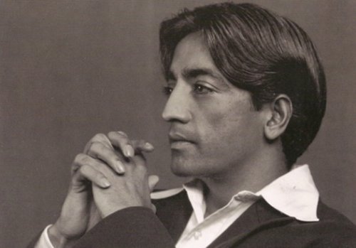 Jiddu Krishnamurti, crossing his hands and staring into the distance.