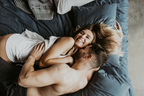 Sex is important in making a elationship work represented by a couple smiling in bed.