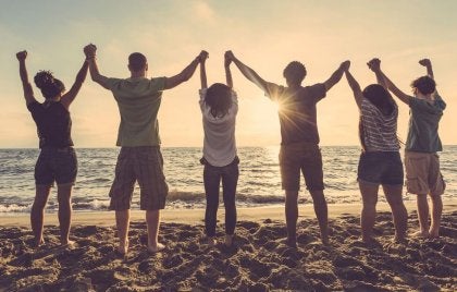 A group of friends holding hands on the beach.