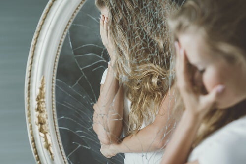 A girl with body image issues looking at herself in front of a broken mirror.