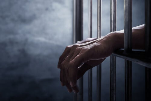 A man with his hands between bars.