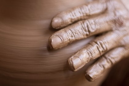 A hand spinning a clay pot.