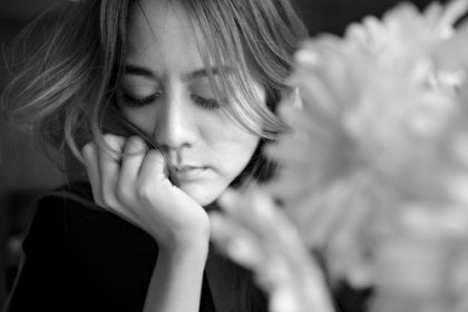 A sad woman next to a flower.