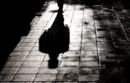 A shadow of a man walking on the sidewalk.