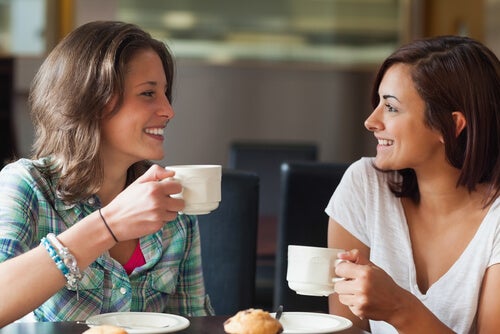 Two friends having coffee and smiling.