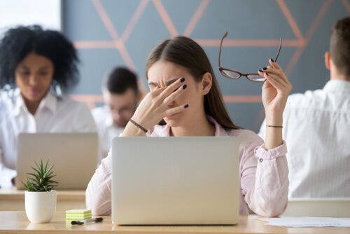 A woman on her computer with a headache.