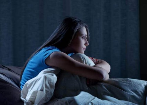 A woman sitting in bed at night.