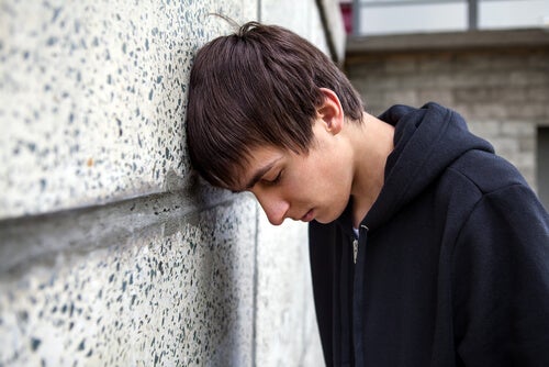 A teenage boy looking down feeling worried.