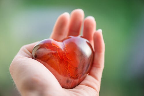 A person holding a heart made of glass.