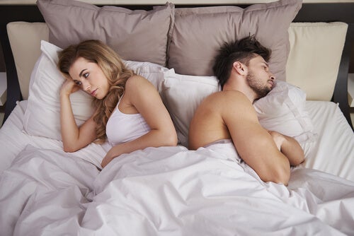 A couple in bed facing away from each other.