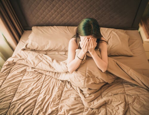 A woman crying in bed.