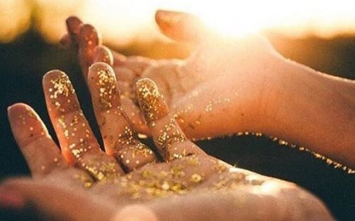 A pair of hands powdered in golden dust.