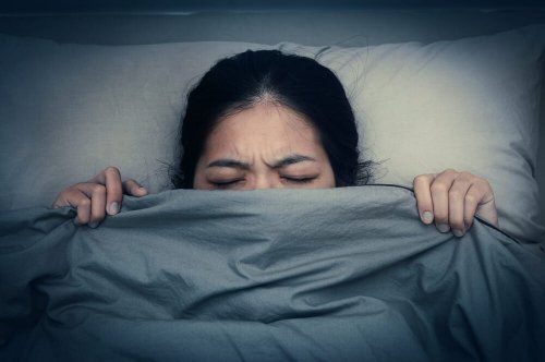 A woman hiding under the sheets.