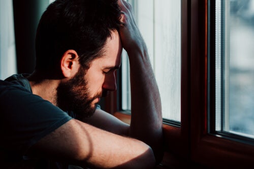 A man with anxiety leaning against the window.