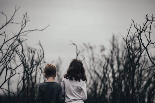 Two kids facing a dreary landscape.