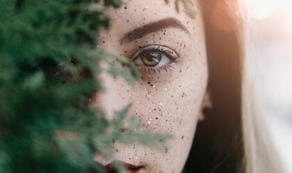 A woman looking out from behind a tree.