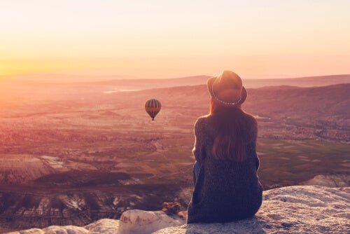 A woman sitting on a mountain thinking about the absence of problems.